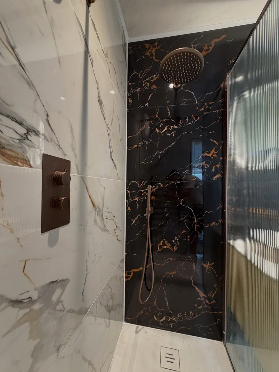 Rainfall shower with copper controls on black marble-effect tiles